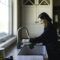 Woman filling up cup at kitchen sink