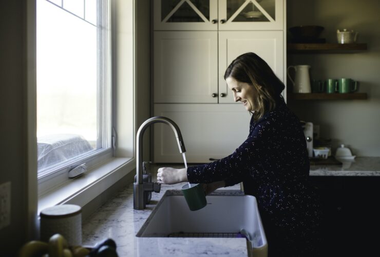 Woman filling up cup at kitchen sink