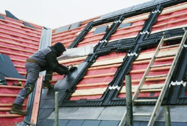 A roofer replacing the tiles on a house roof.