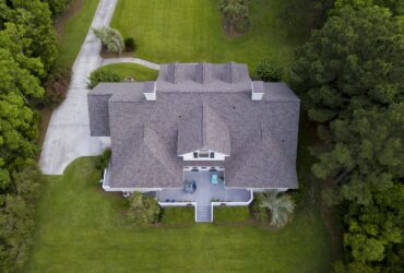 Aerial view of large home with new roof on beautiful property.
