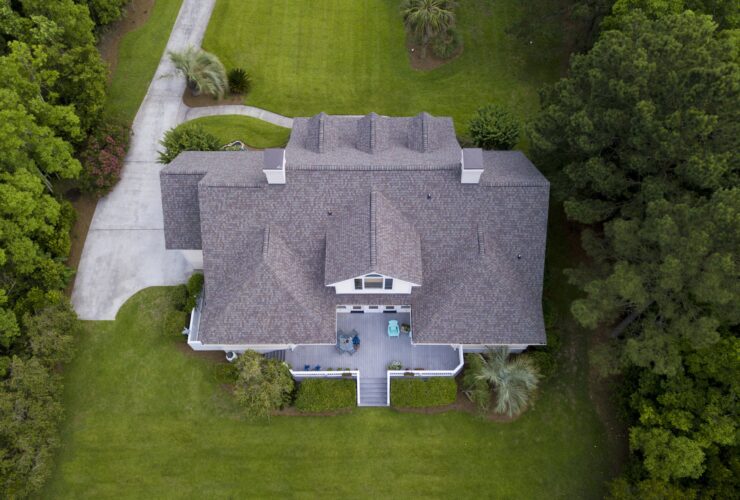 Aerial view of large home with new roof on beautiful property.