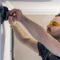An electrician is mounting electric sockets on the white wall indoors.