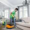 Indian male cleaner cleaning sofa with modern vacuum cleaner