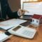 Property sales staff submit land mortgage contract documents to home buyers for sign.
