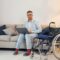 With laptop on the legs. Disabled man in wheelchair is at home