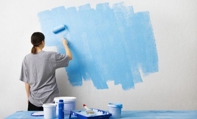 Woman painting interior wall with paint roller