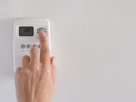 Woman’s hand adjusting digital thermostat settings
