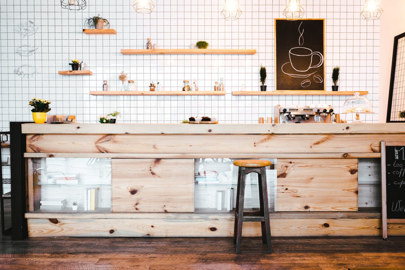 wooden brown bar counter with plants and cupcakes, drawing on shelf in coffee house