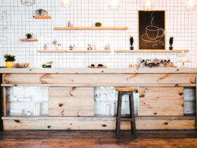 wooden brown bar counter with plants and cupcakes, drawing on shelf in coffee house