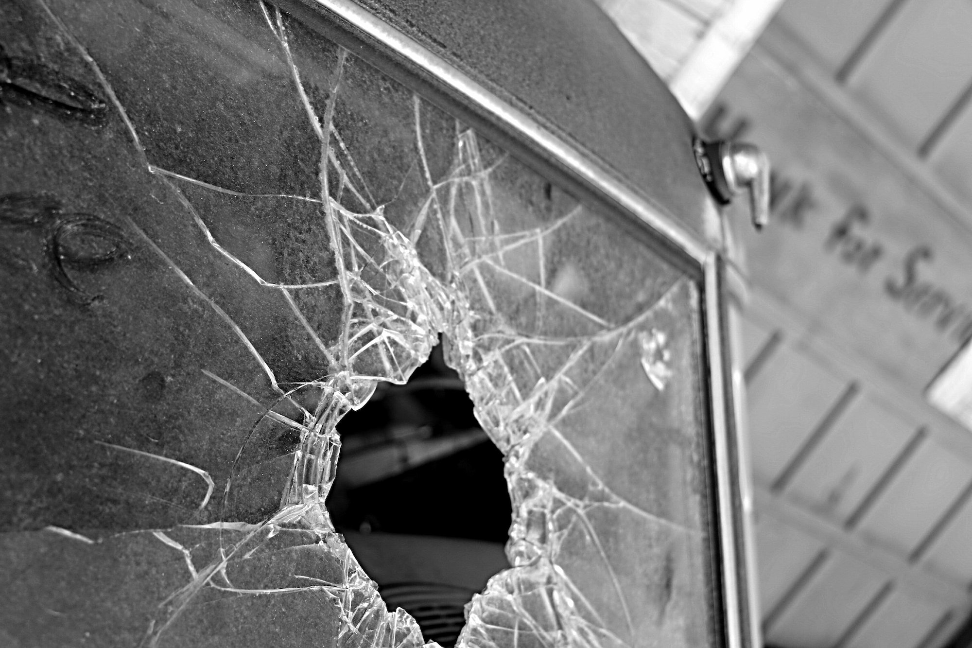 Broken Glass: Monochromatic image of shattered windshield of vintage car in old garage.