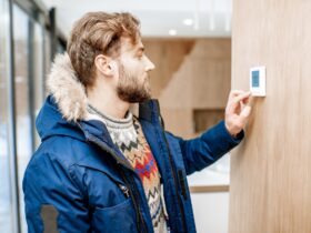 Man adjusting temperature with thermostat at home