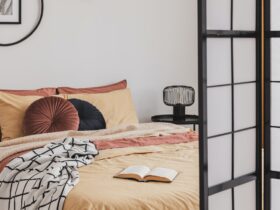 Open book on yellow duvet in small cozy bedroom interior with ginger accents