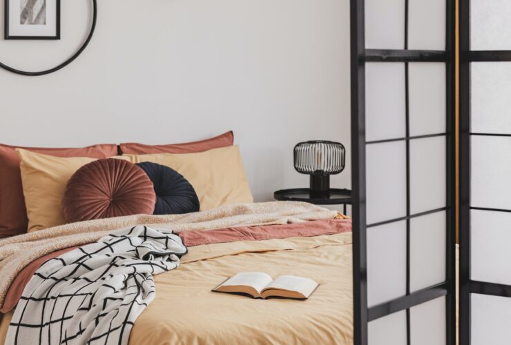 Open book on yellow duvet in small cozy bedroom interior with ginger accents