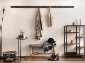 The stylish composition of cosy entryway with grey bench, black consola, hanger and lamp.