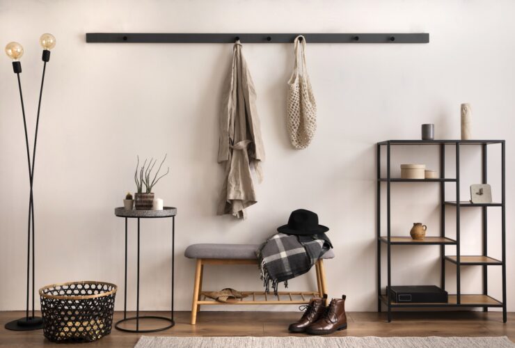The stylish composition of cosy entryway with grey bench, black consola, hanger and lamp.