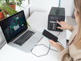 Young woman with portable power station at table in office.