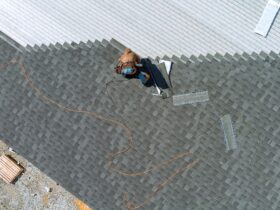 A asphalt shingles installation on the roof roofer is nailing asphalt shingles to roofing constructi
