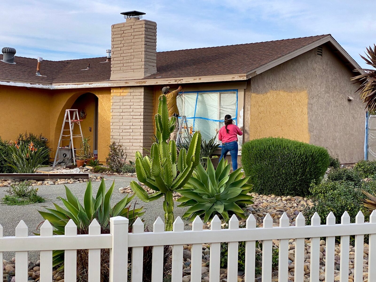 A couple doing home maintenance painting the exterior of their house together