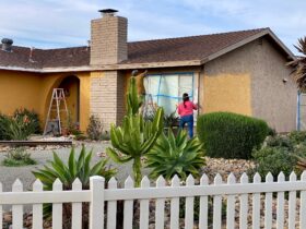 A couple doing home maintenance painting the exterior of their house together