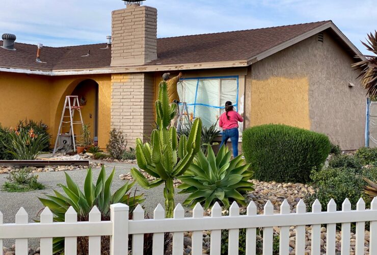 A couple doing home maintenance painting the exterior of their house together