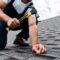 cropped view of handyman in uniform holding hammer while repairing roof