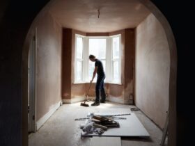 A builder sweeping and tidying up in a renovated replastered house with an archway.