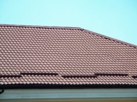 A fragment of a roof from a metal tile of dark red color. Quality Roofing
