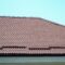 A fragment of a roof from a metal tile of dark red color. Quality Roofing