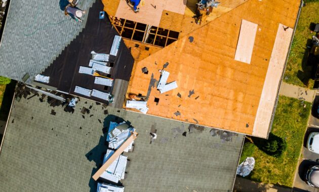 A worker replace shingles on the roof of a home repairing the roof of home