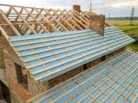 Aerial view of a brick house with wooden roof frame under construction.