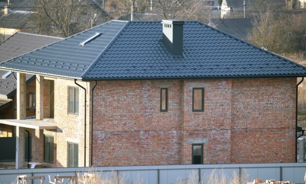 Brick house with roof top covered with metallic shingles.