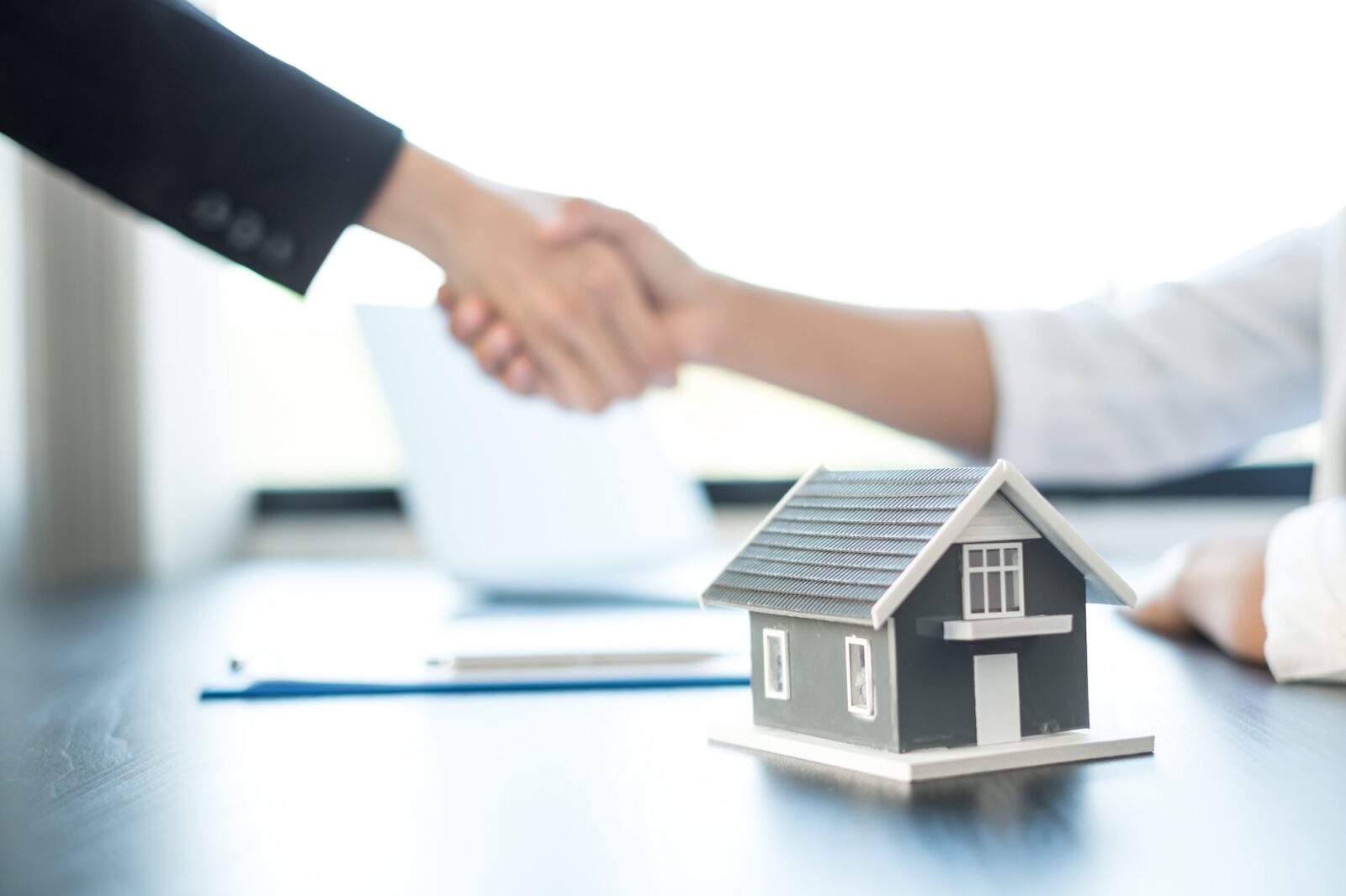 Businessmen and brokers real estate agents shake hand after completing negotiations to buy houses