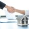Businessmen and brokers real estate agents shake hand after completing negotiations to buy houses