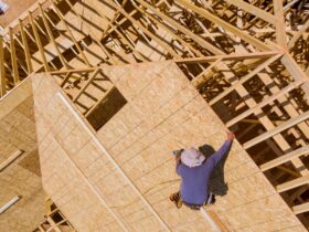 Carpenter with nailing plywood on roof of the house