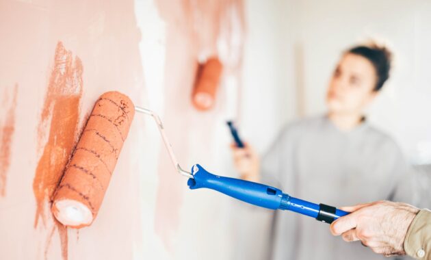 Couple renovating the house. Couple painting a wall