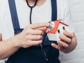 cropped shot of craftsman checking house figure by stethoscope, home inspection concept