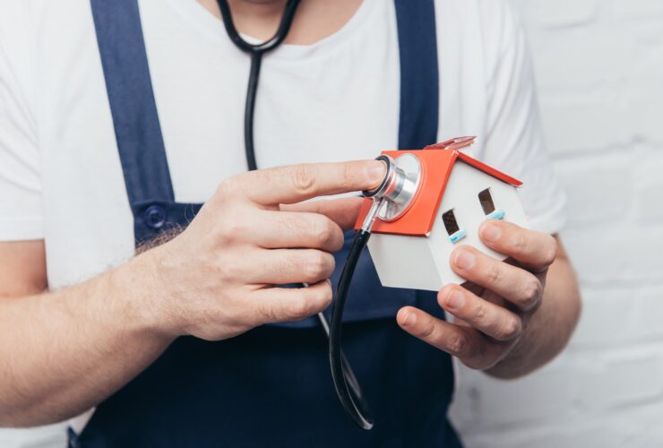 cropped shot of craftsman checking house figure by stethoscope, home inspection concept