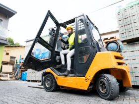 Female forklift truck driver outside a warehouse.
