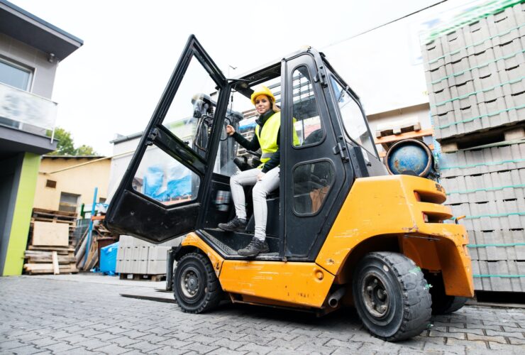 Female forklift truck driver outside a warehouse.