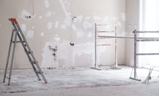 Ladder and construction equipment standing in empty room illuminated by bright sunlight
