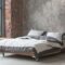 Loft style bedroom interior with bed, gray design, brick texture and concrete wall