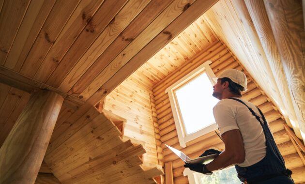 Male worker clicking on laptop while checking house walls