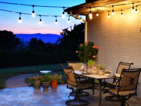 Outdoor living space with dining table set for dinner with wine, lights and a view of the mountains