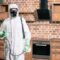 pest control worker standing with sprayer in kitchen
