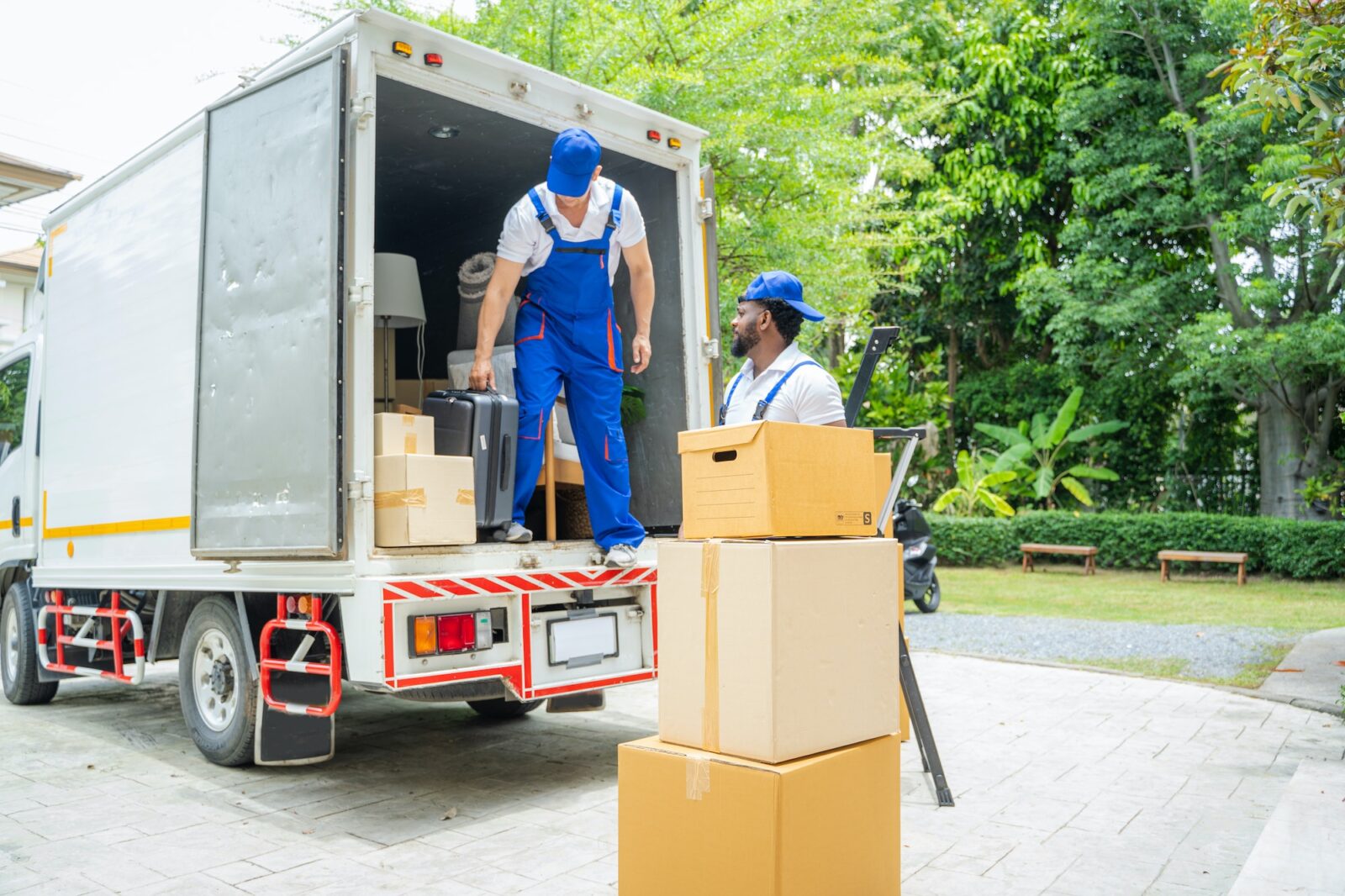 Removal company workers unloading Boxes From Truck Into New Home On Moving Day.