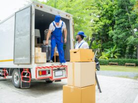 Removal company workers unloading Boxes From Truck Into New Home On Moving Day.