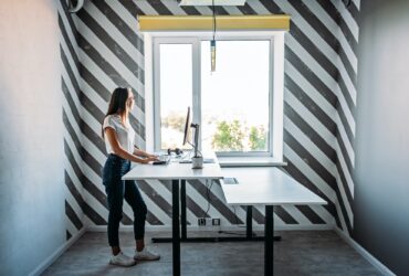Standing desk for work from home or in office. Young woman programmer working