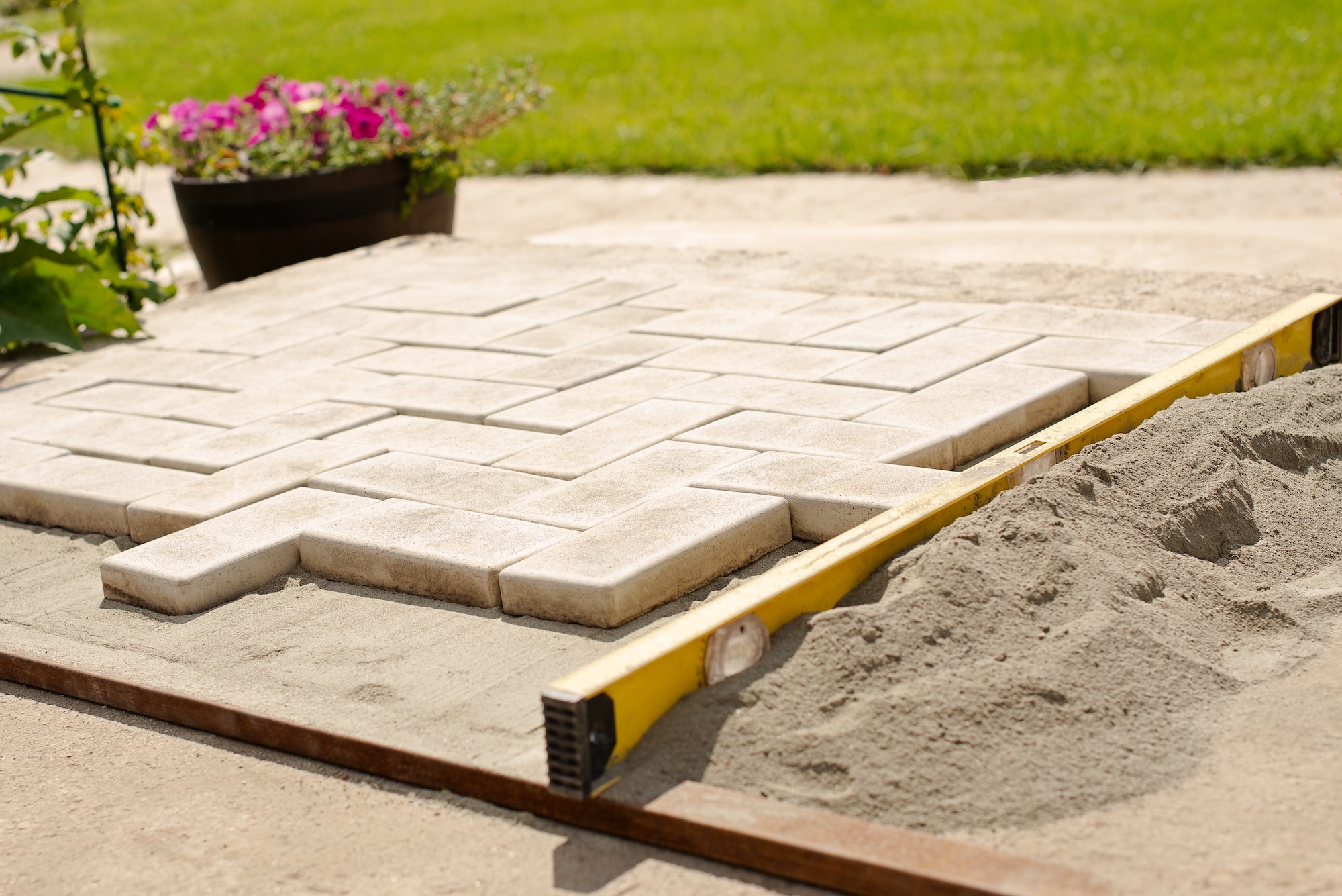The master lays paving stones in layers. Garden brick pathway paving by professional paver worker.