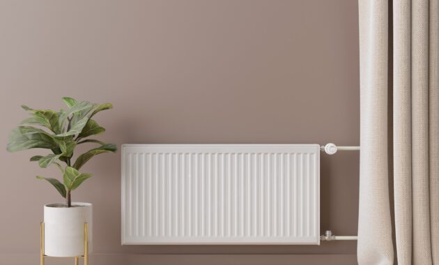 White heating radiator with thermostat on brown wall. Central heating system. Free, copy space