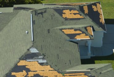 Wind damaged house roof with missing asphalt shingles after hurricane Ian in Florida.